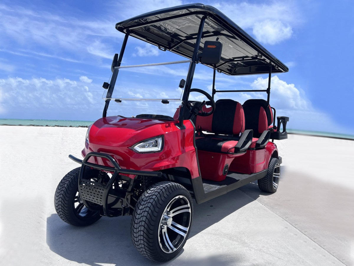 Red golf cart with black roof parked on a sunny beachside path.