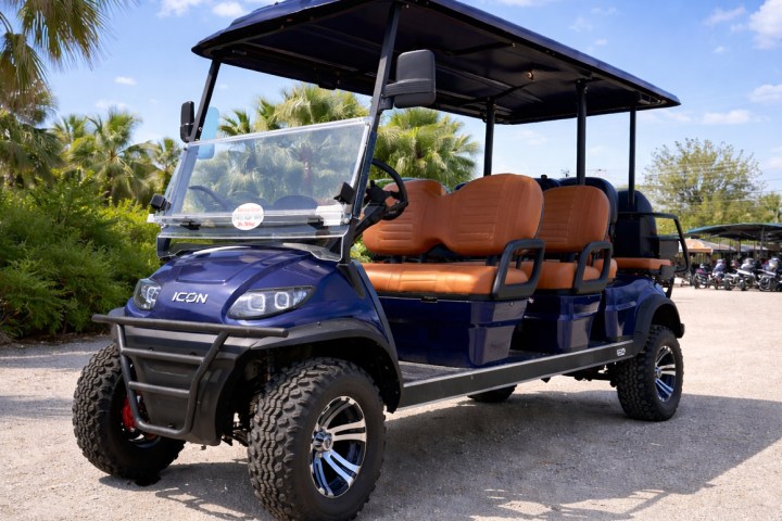 Blue golf cart with tan seats parked outdoors on a sunny day.